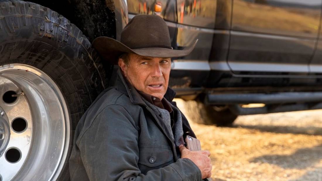 Kevin Costner as John Dutton sitting, leaning on his car wounded in Yellowstone Season 4, Episode 1.
