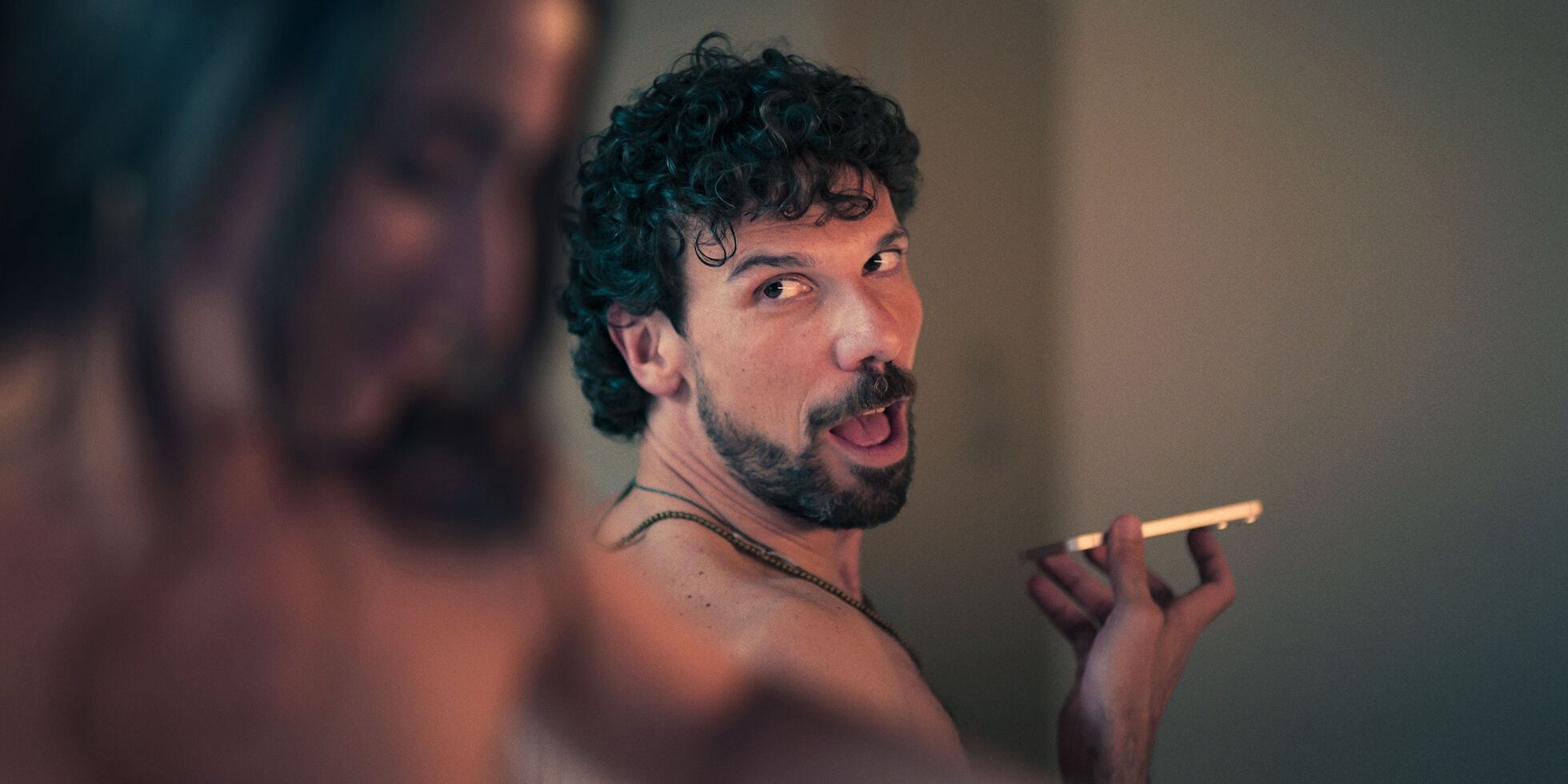 A man talks into a smartphone while looking back at a woman in Italian Netflix's 'Real Men'.