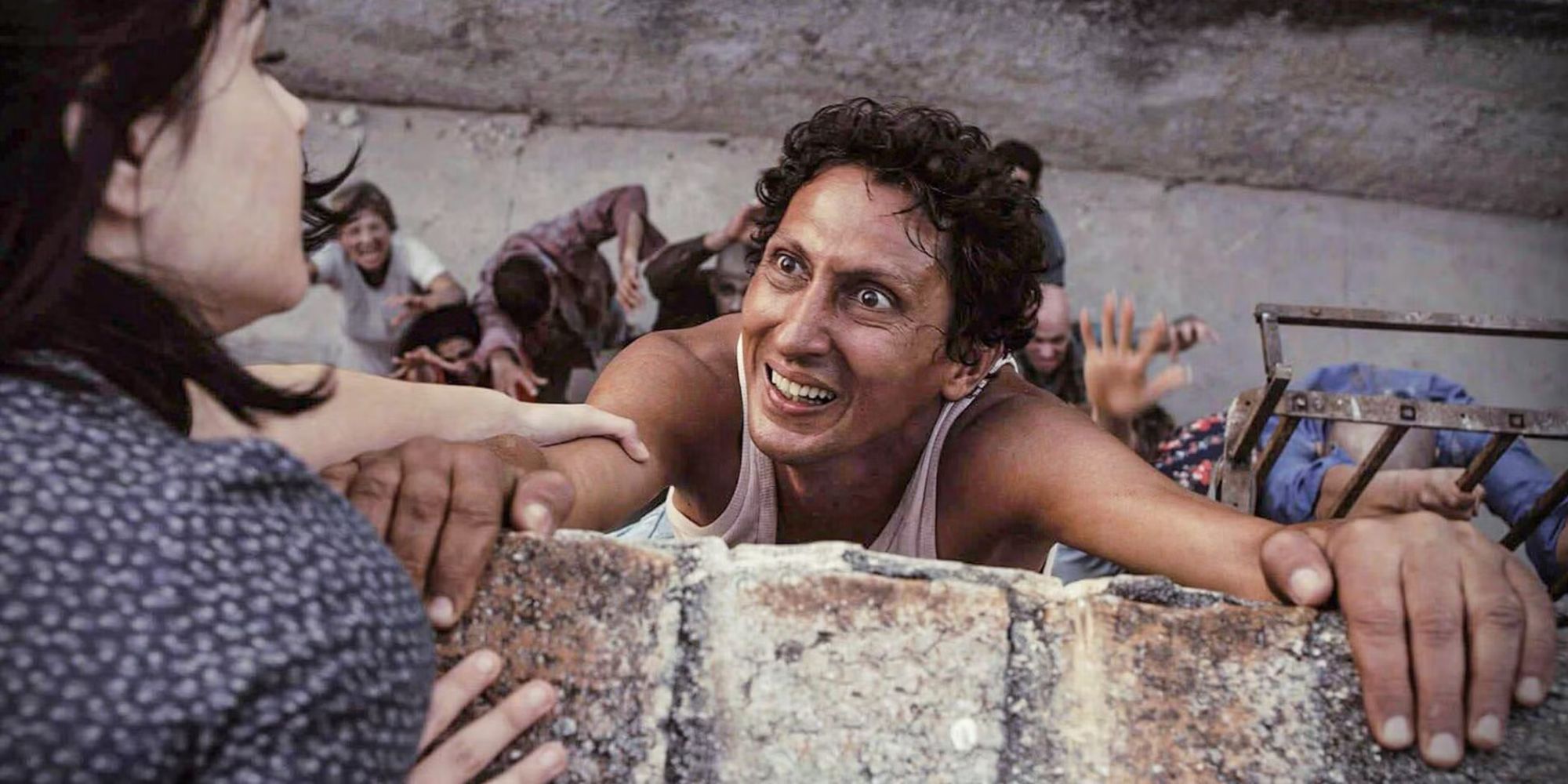 Alexis Díaz, smiling while hanging from a ledge with zombies beneath him, in 'Juan of the Dead'.