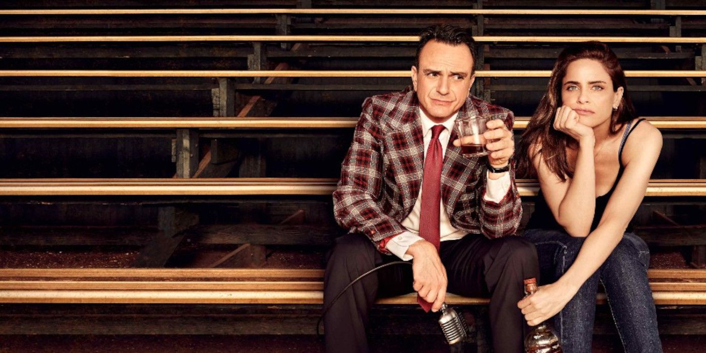 Jim sits on the bleachers with a drink in hand next to Jules on Brockmire.