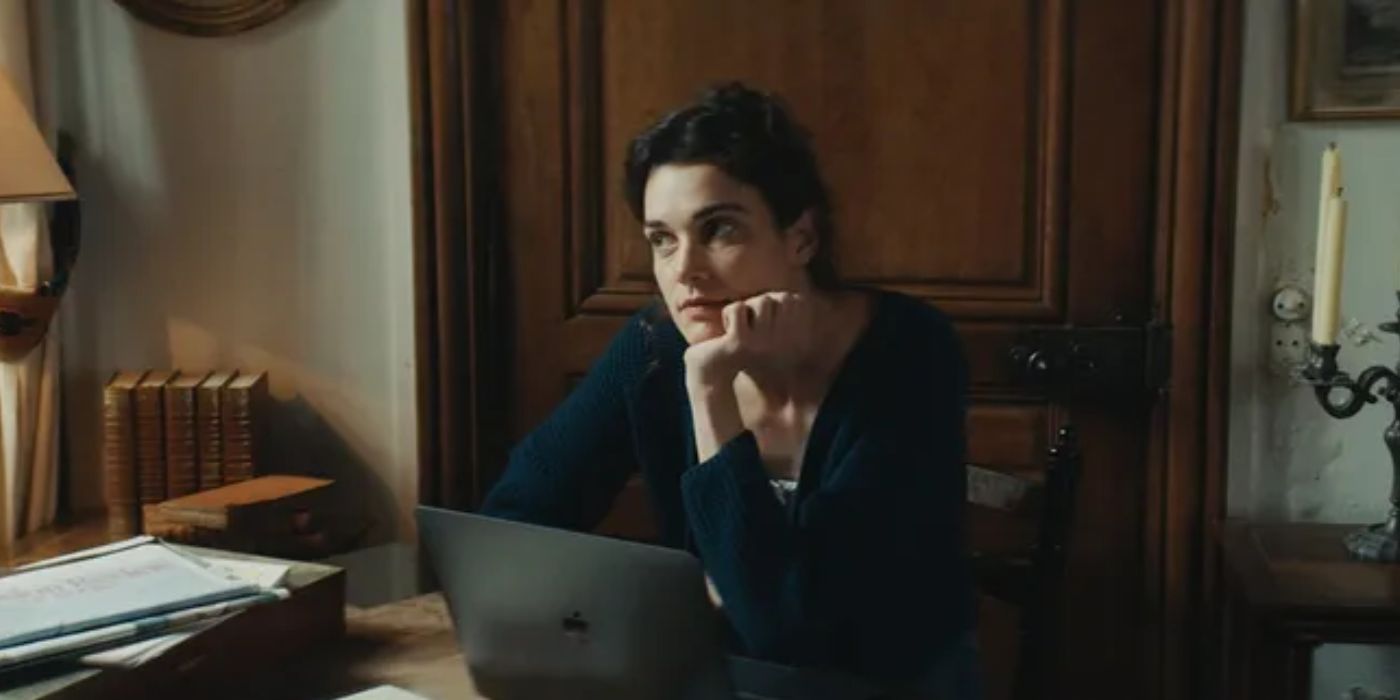 Camille Rutherford as Agathe looking out a window in front of an open laptop in Jane Austen Wrecked My Life.