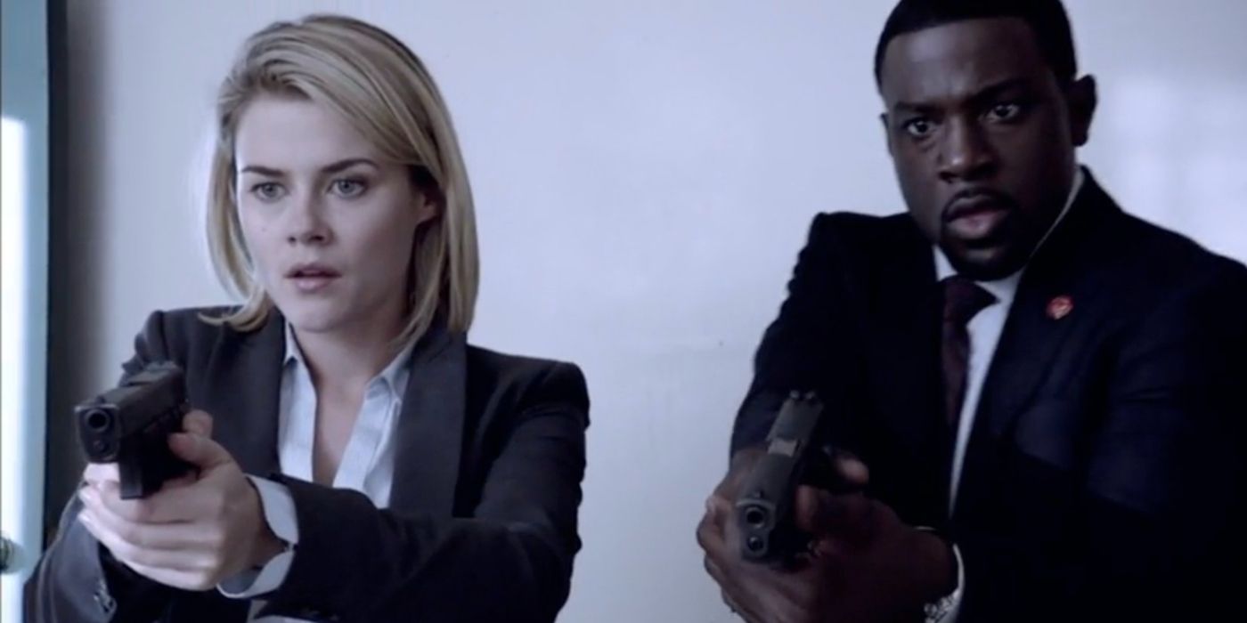 Rachael Taylor como agente Susie Dunn e Lance Gross, agente Marcus Finley em ternos e segurando armas em "Crise."