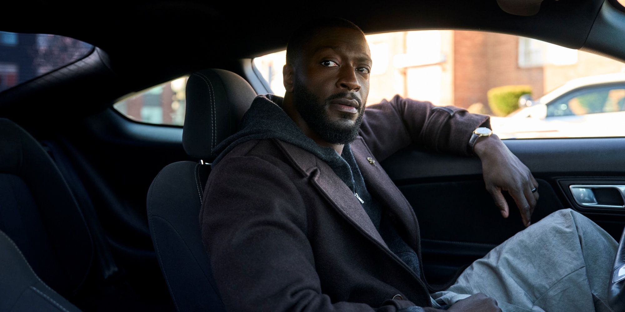Aldis Hodge as Detective Alex Cross sitting in the driver's seat of a car in Season 1 of Cross.