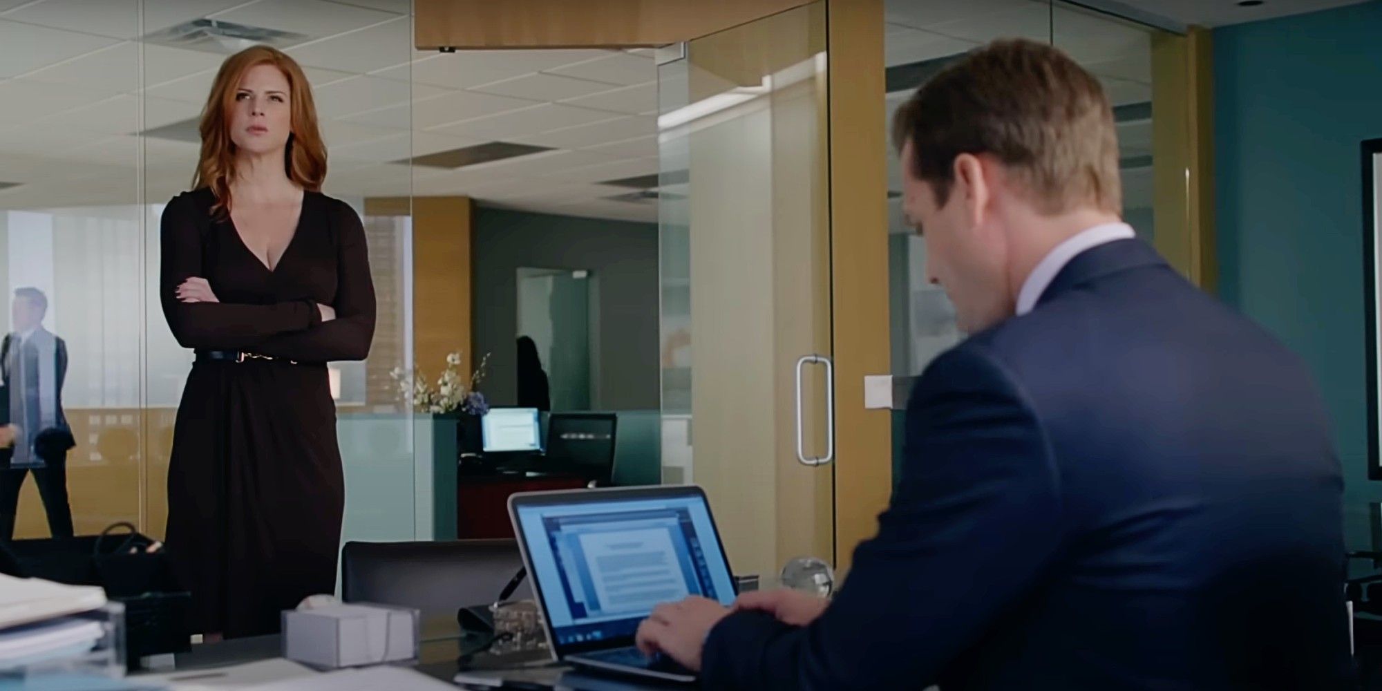 Donna Paulsen standing in Harvey Specter's office while he types at his laptop in Suits Season 2, Episode 1.