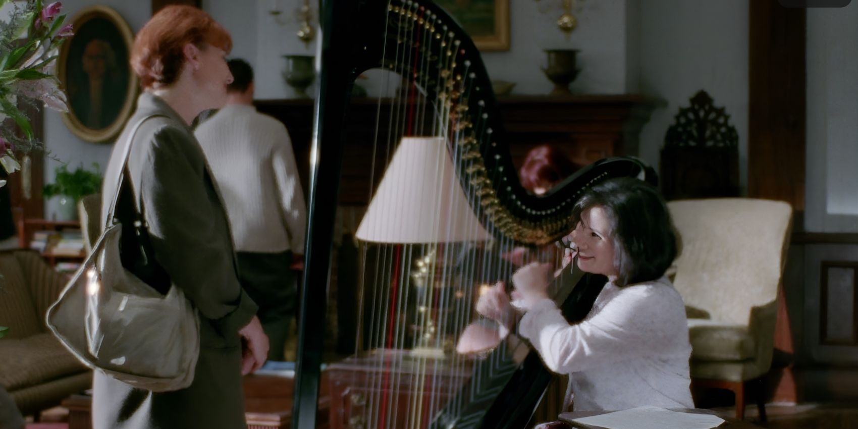 Drella (Alex Borstein) playing the harp for a guest in Gilmore Girls.