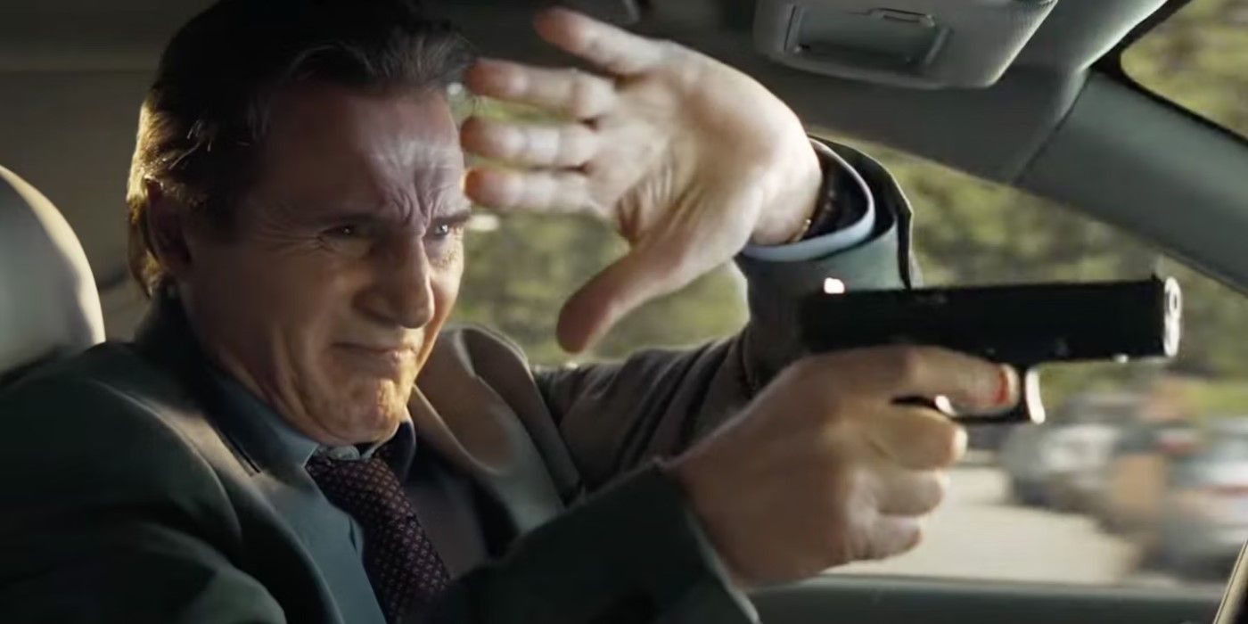 Frank Drebin Jr. (Liam Neeson) blocking his eyes from sunlight while aiming his gun, while driving, in The Naked Gun.