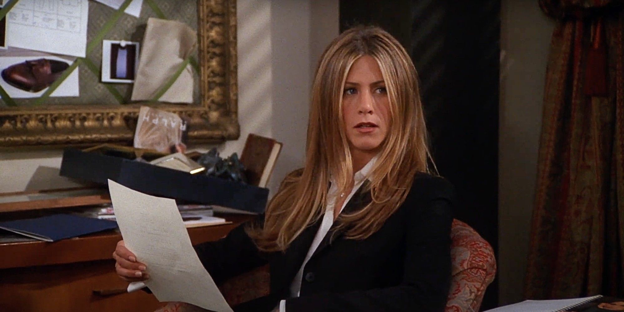 Rachel Green sitting behind her desk and going over a resume in Friends Season 7 The One with the Assistant.