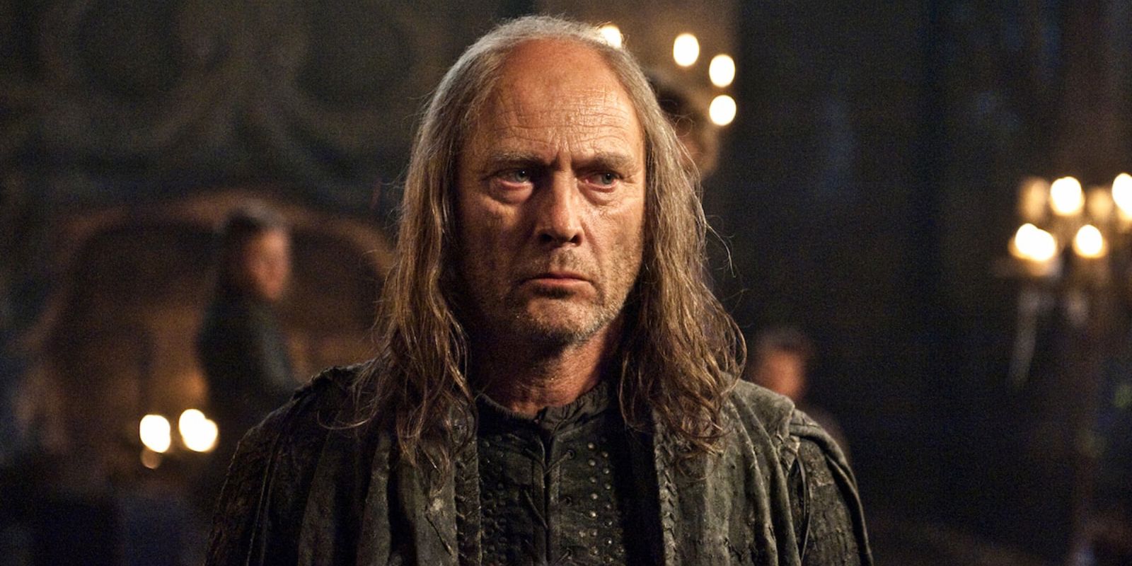 Balon Greyjoy looks worried, standing in a large room with candles in Game of Thrones.