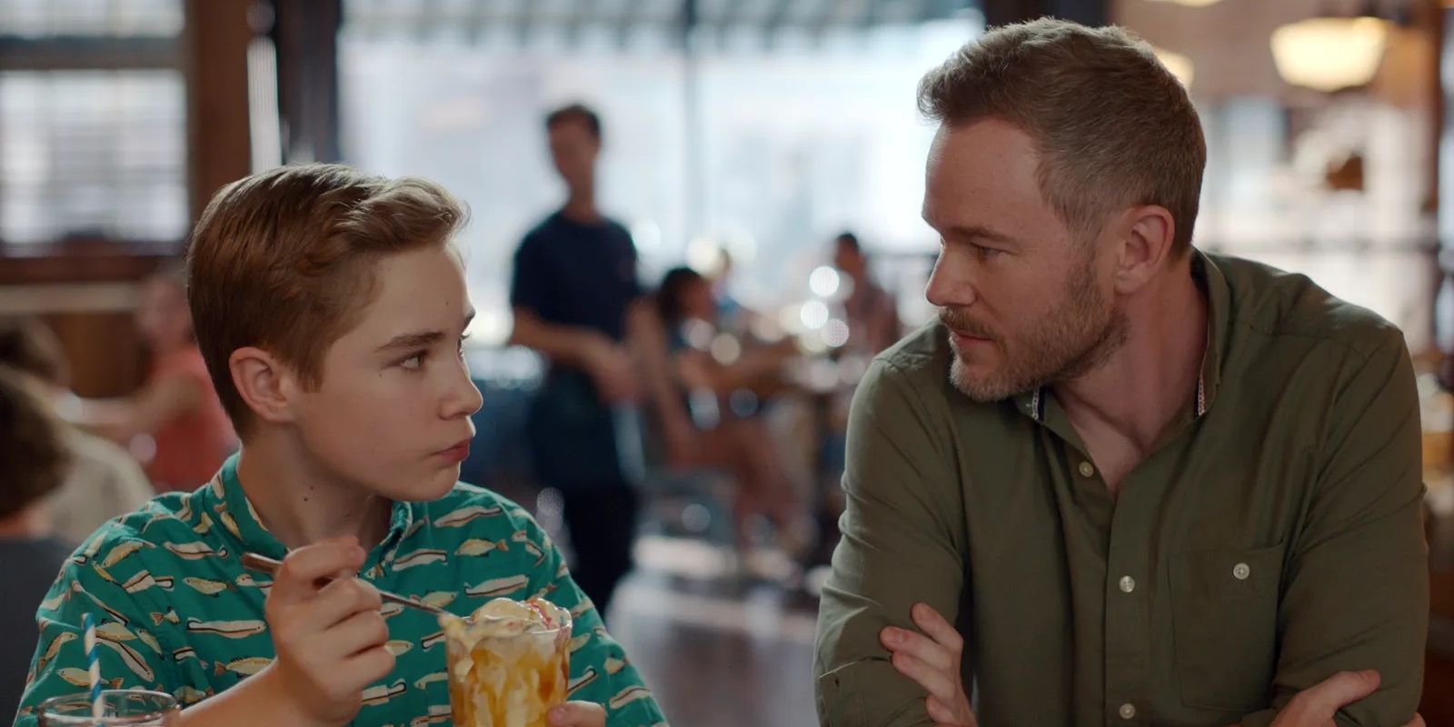 Austin (Diesel La Torraca) eats ice cream while looking at Gil (Aaron Ashmore) in Ginny & Georgia Season 3