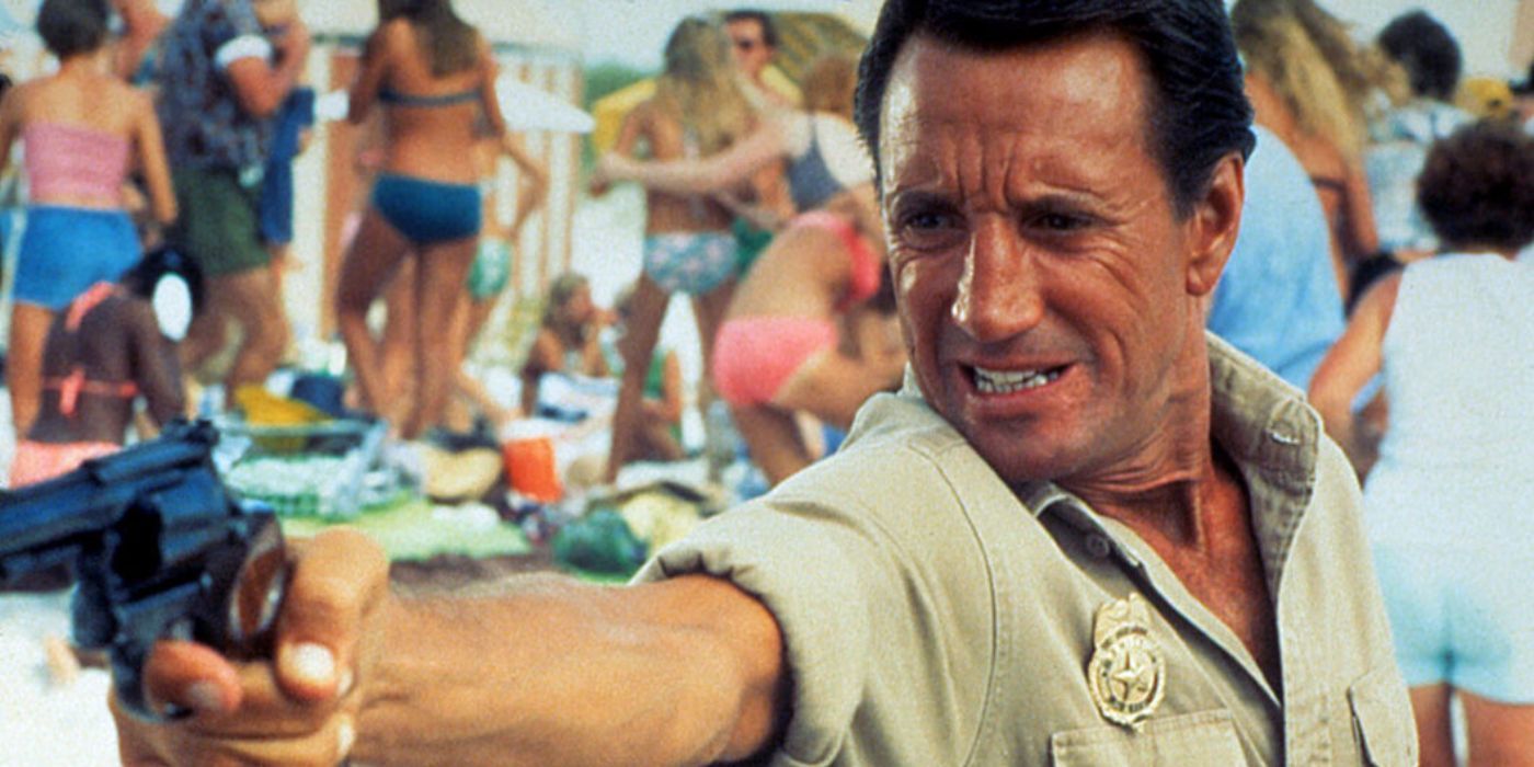 Roy Scheider as Chief Brody firing a gun at the beach in Jaws 2.