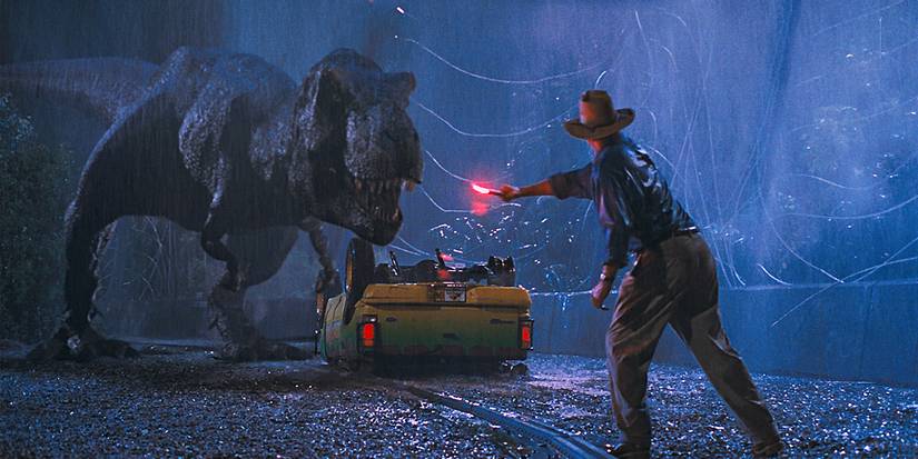 Aktieris Sems Neils kā Alans Grants, kas izceļas lietū, novērš uzmanību no t.rex ar uzliesmojumu Jurassic parkā.
