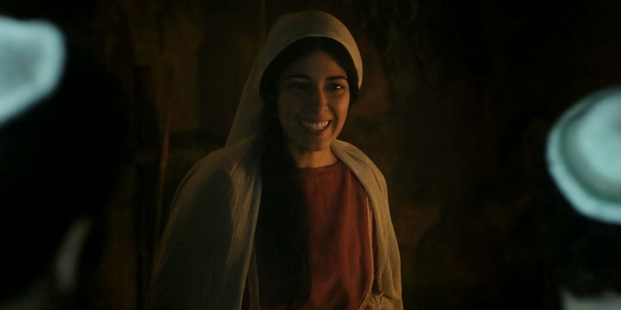 Elizabeth Tabish como Maria Madalena sorrindo e acolhe os visitantes em sua casa em uma cena de The escolhido.
