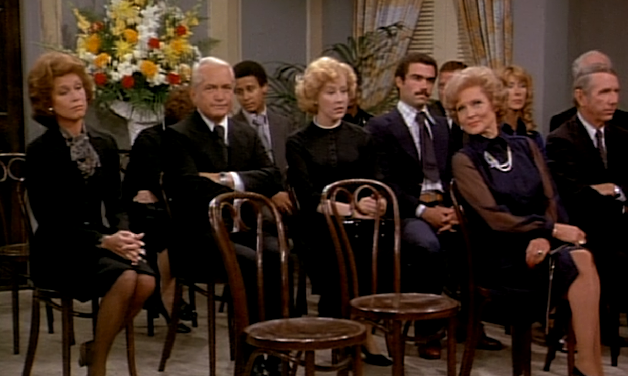 Mary and her co-workers sit at a funeral in The Mary Tyler Moore Show.
