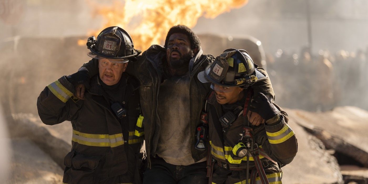 Mouch (Christian Stolte) and Ritter (Daniel Kyri) walk a victim to safety with fire raging behind in Chicago Fire episode "In the Trenches, Part I."