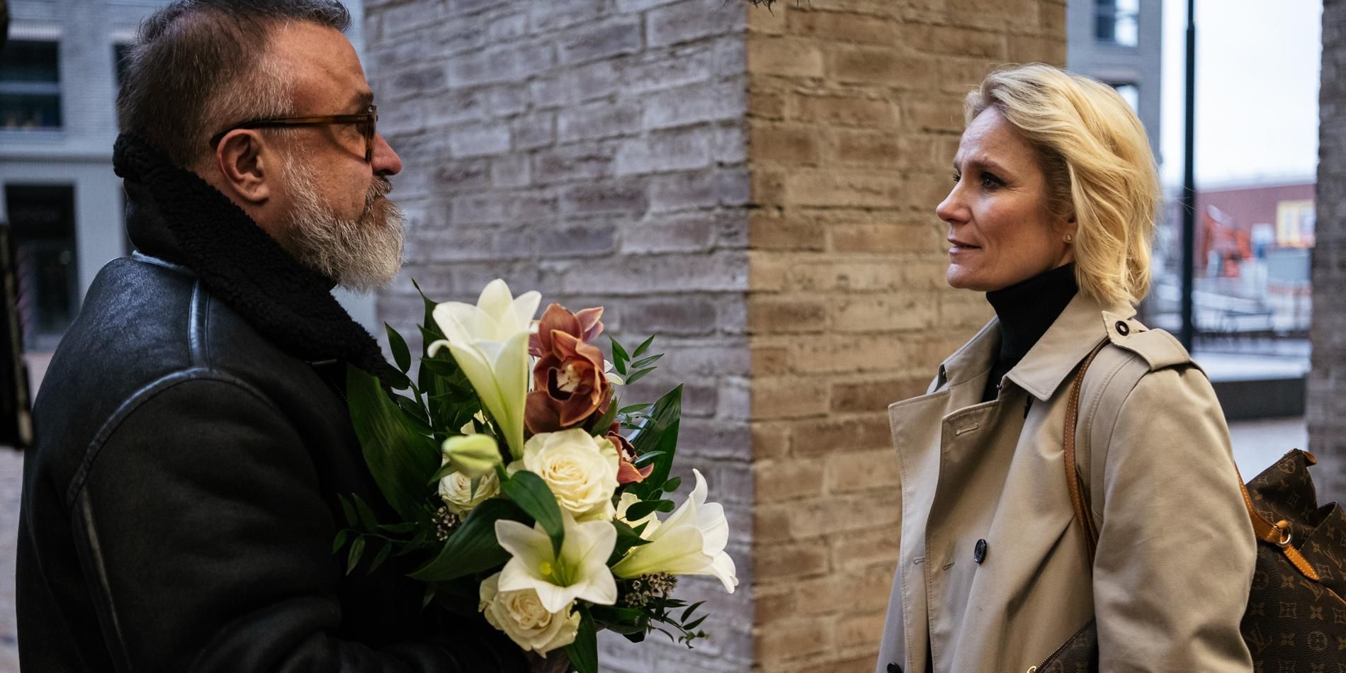 A man holding flowers stands in front of a woman in a Queen of F*cking Everything scene.