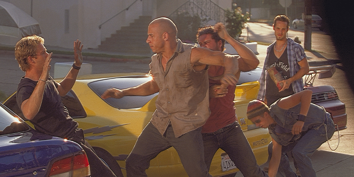Paul Walker with hands raised as Vin Diesel winds up to punch him in The Fast and the Furious, 2001.