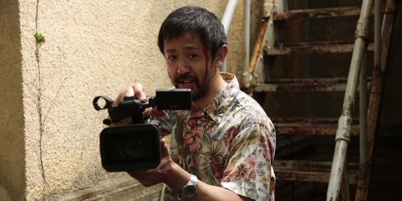 An injured man holds up a film camera in One Cut of the Dead.