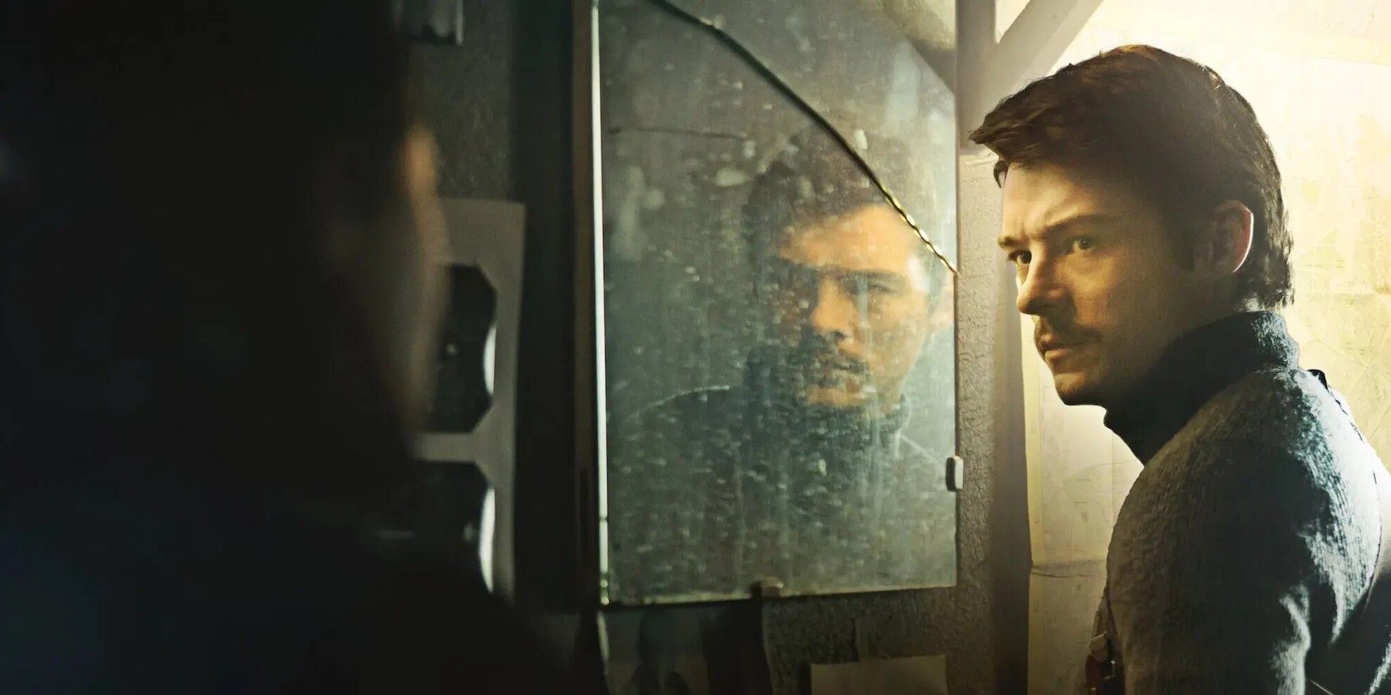 Tomasz Zietek as Robert looking at a man while next to a dirtied mirror  in 'Operation Hyacinth'