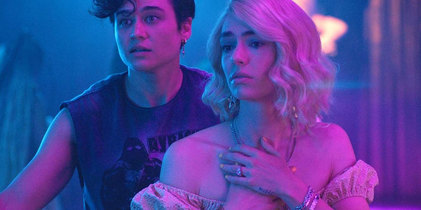 Dre and Misti, played by actors Katy O'Brian and Sarah Coffey, bathed in a blue light and looking disturbed in Queens of the Dead.