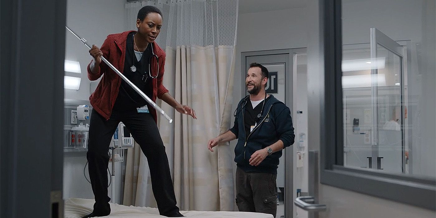 Dr. Collins stands on a bed wielding a pole against an escaped rat while Dr. Robby laughs at her in The Pitt.