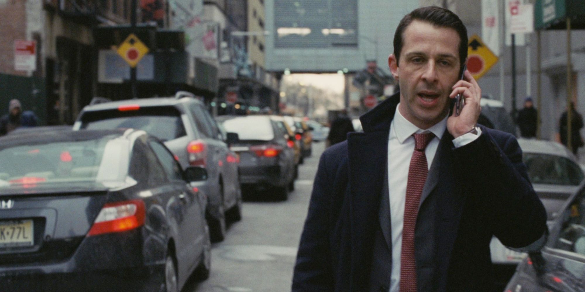A man walks down a busy city street while talking on the phone in Succession episode Which Side Are You On.