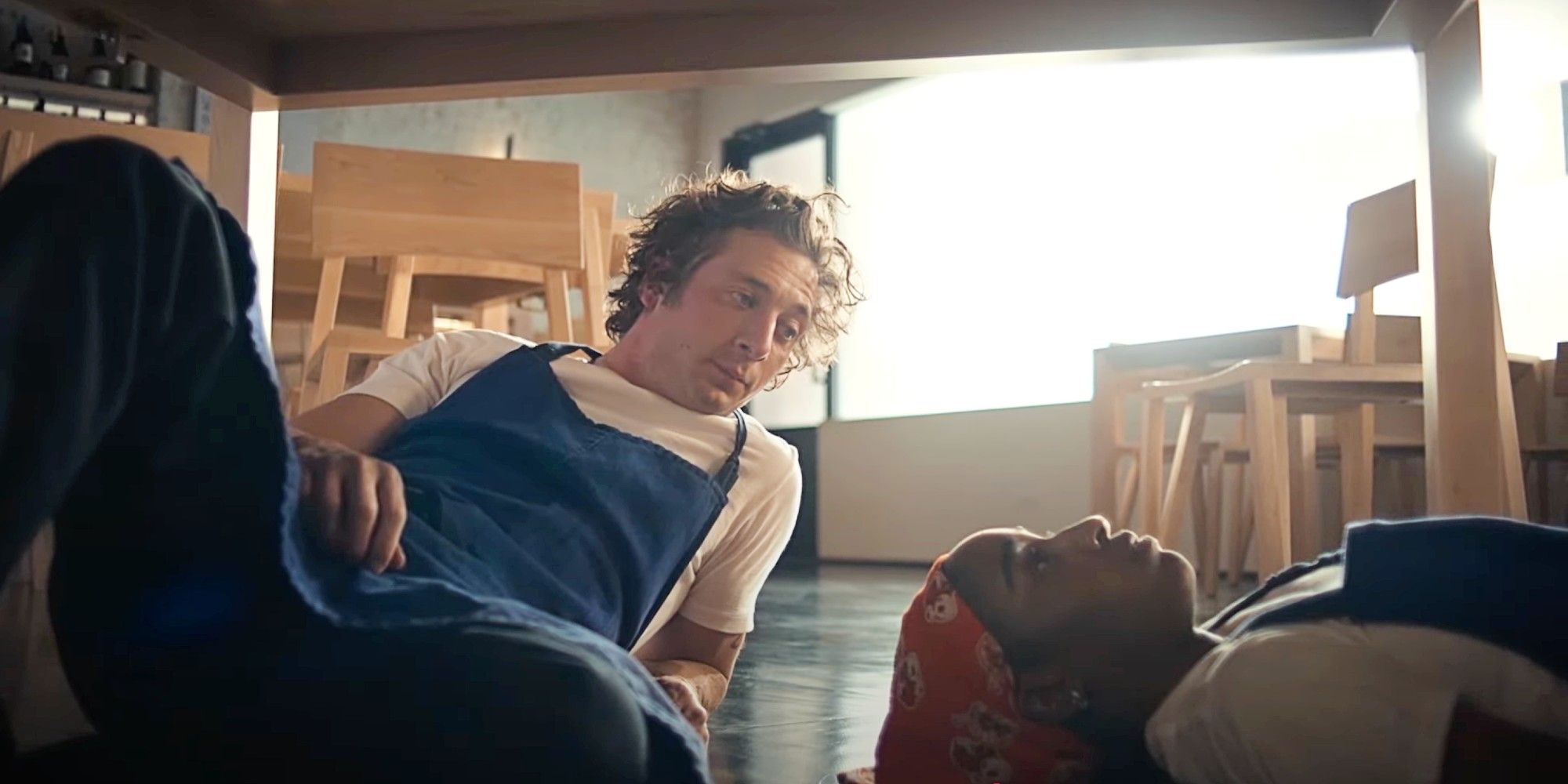 Carmy Berzatto and Sydney Adamu fixing a table from underneath in The Bear Season 2