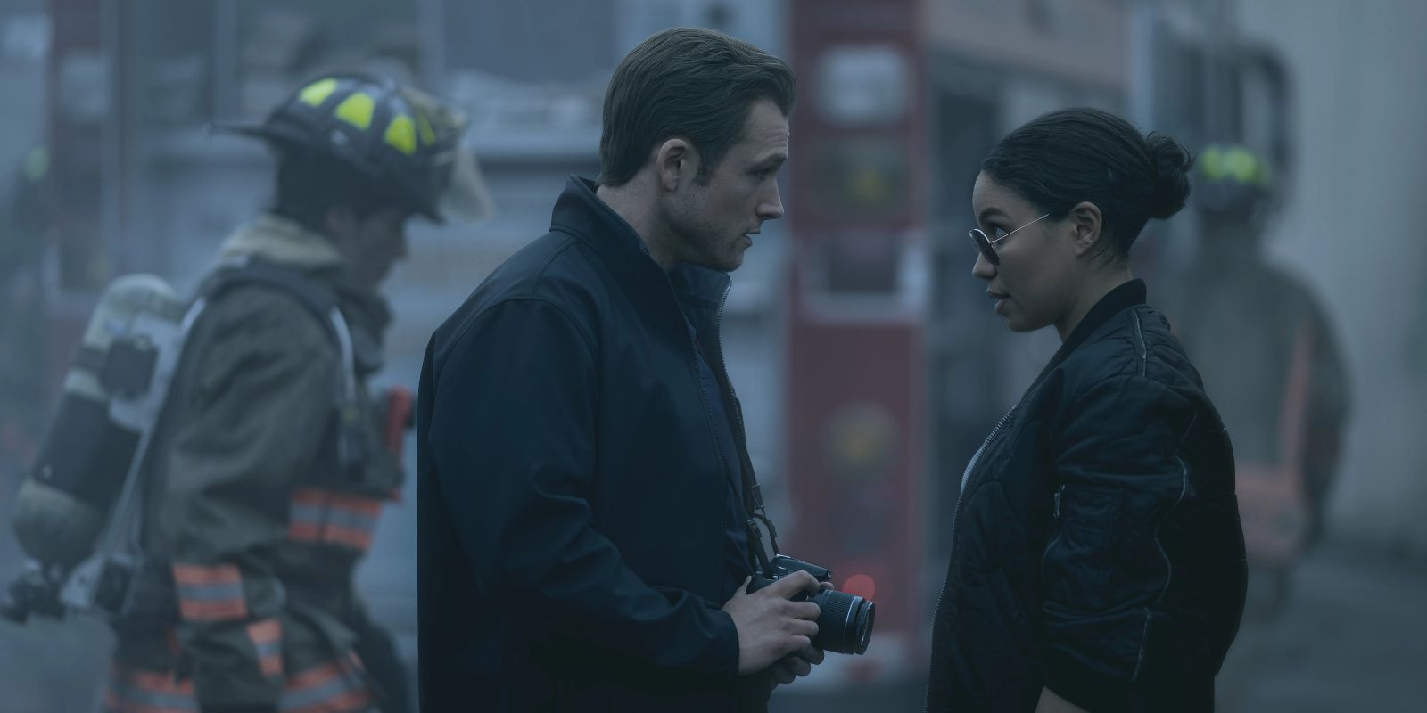 Taron Egerton and Jurnee Smollett talking with an ambulance and firemen in the bacground in Smoke