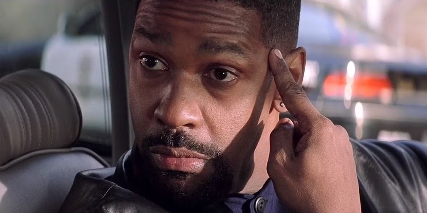 Denzel Washington com um dedo no templo em um carro em uma cena desde o dia do treinamento.