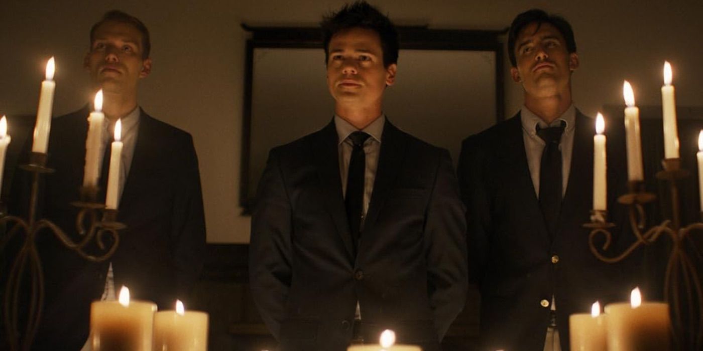 Three frat members behind candles