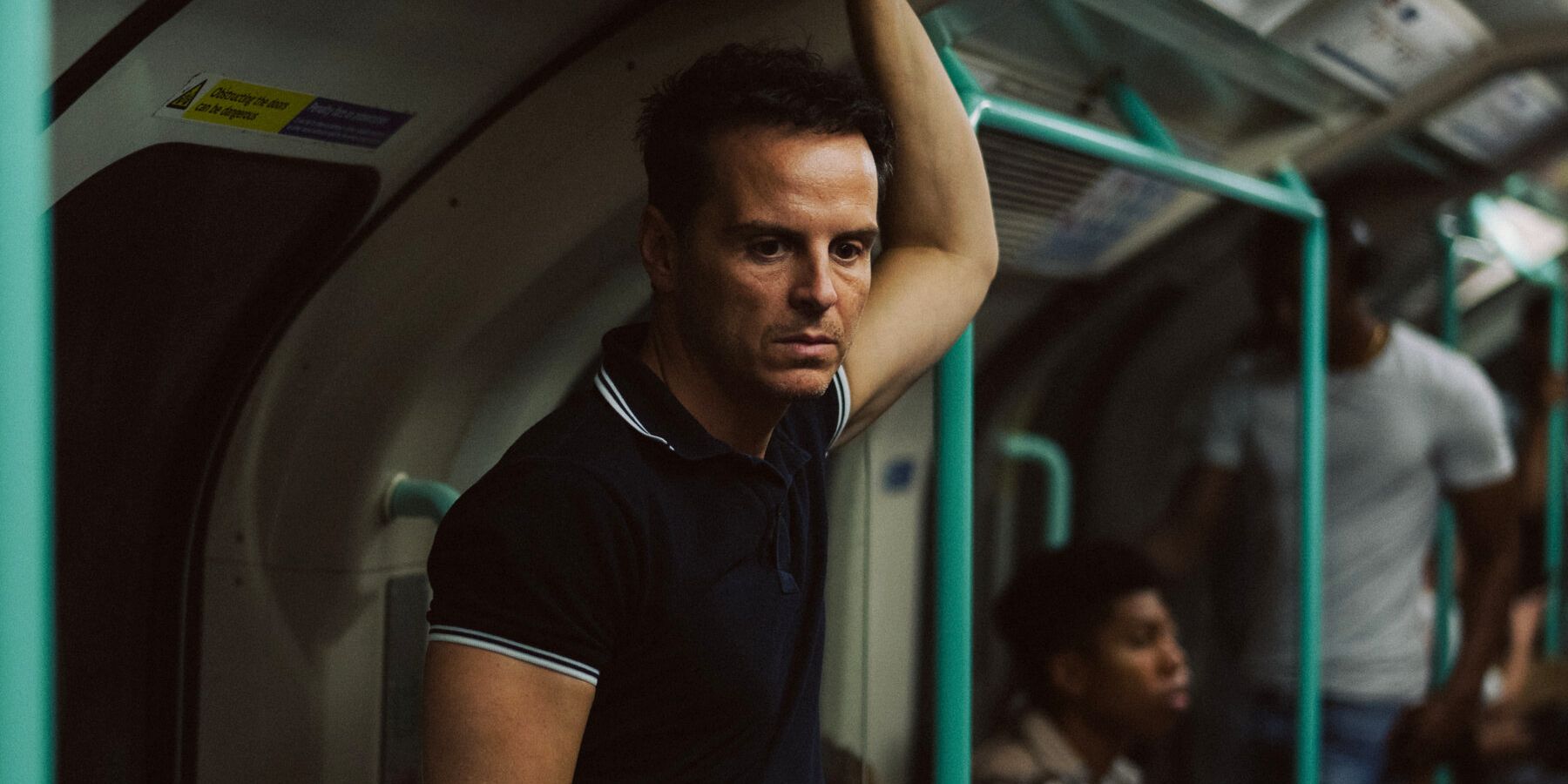 Andrew Scott em pé em um trem e parecendo vazio em todos nós estranhos (2023)