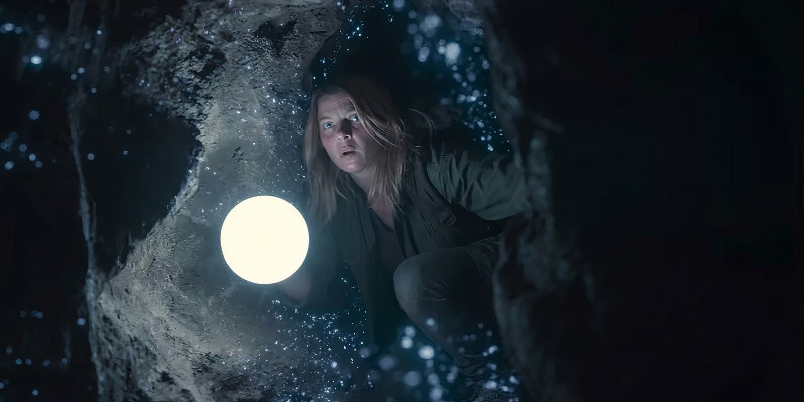 A woman holding a light in a cave crevice in the series Dark Season 2 finale.