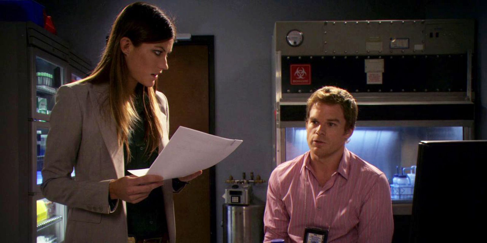 Debra holding some papers and looking over her seated brother in a dark room in Sin of Omission (2011)