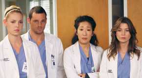 Greys Anatomy cast of characters standing with somber expressions.