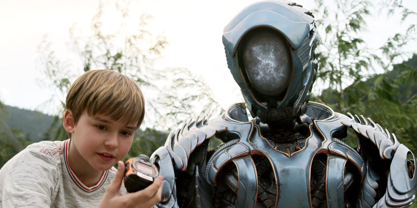 Brian Steele como o robô fica ao lado de Maxwell Jenkins, como Will, enquanto olha para um dispositivo em Lost in Space.
