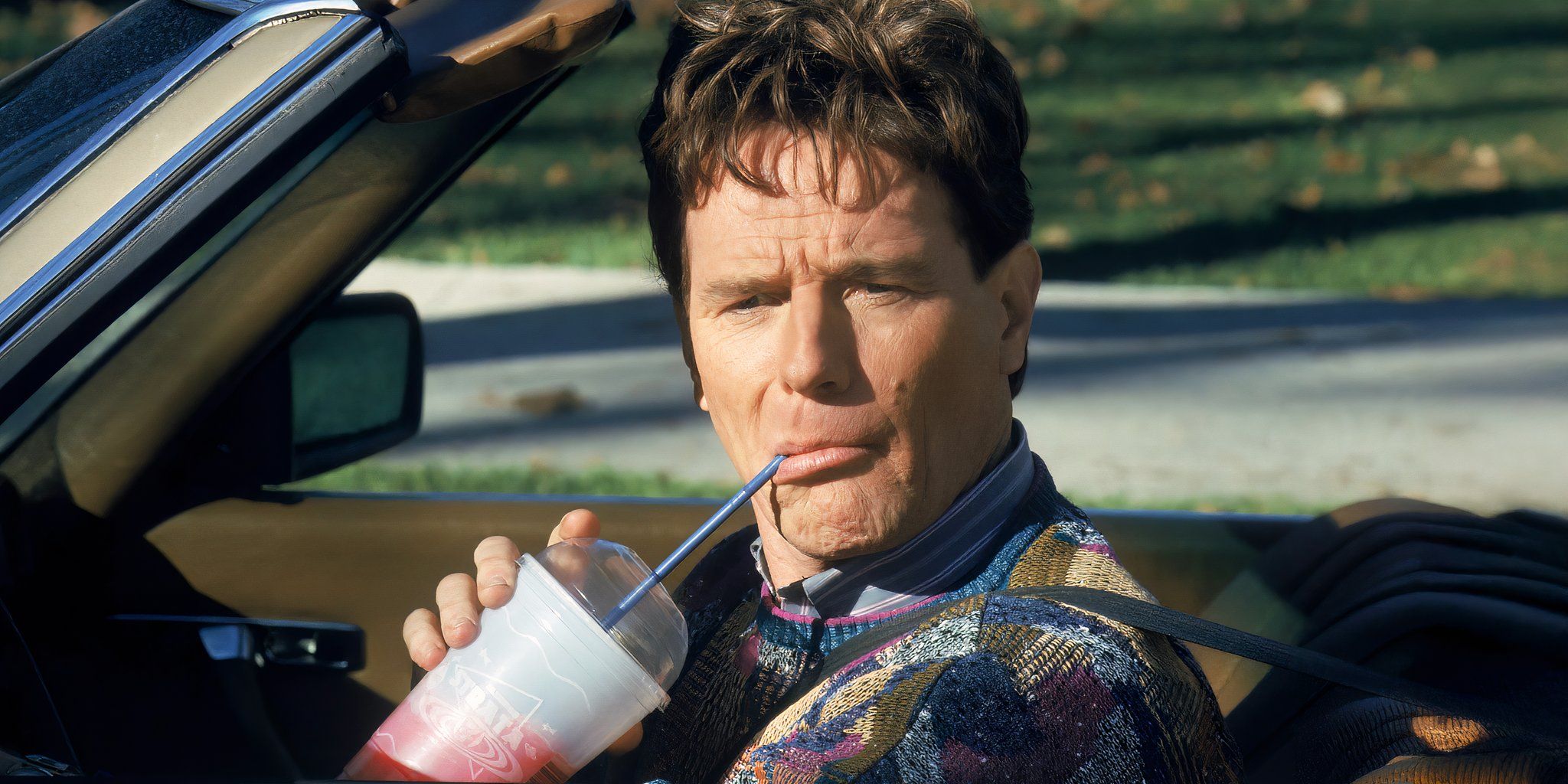 Bryan Cranston as Hal in Malcolm in the Middle sips a slurpy while looking out his car window