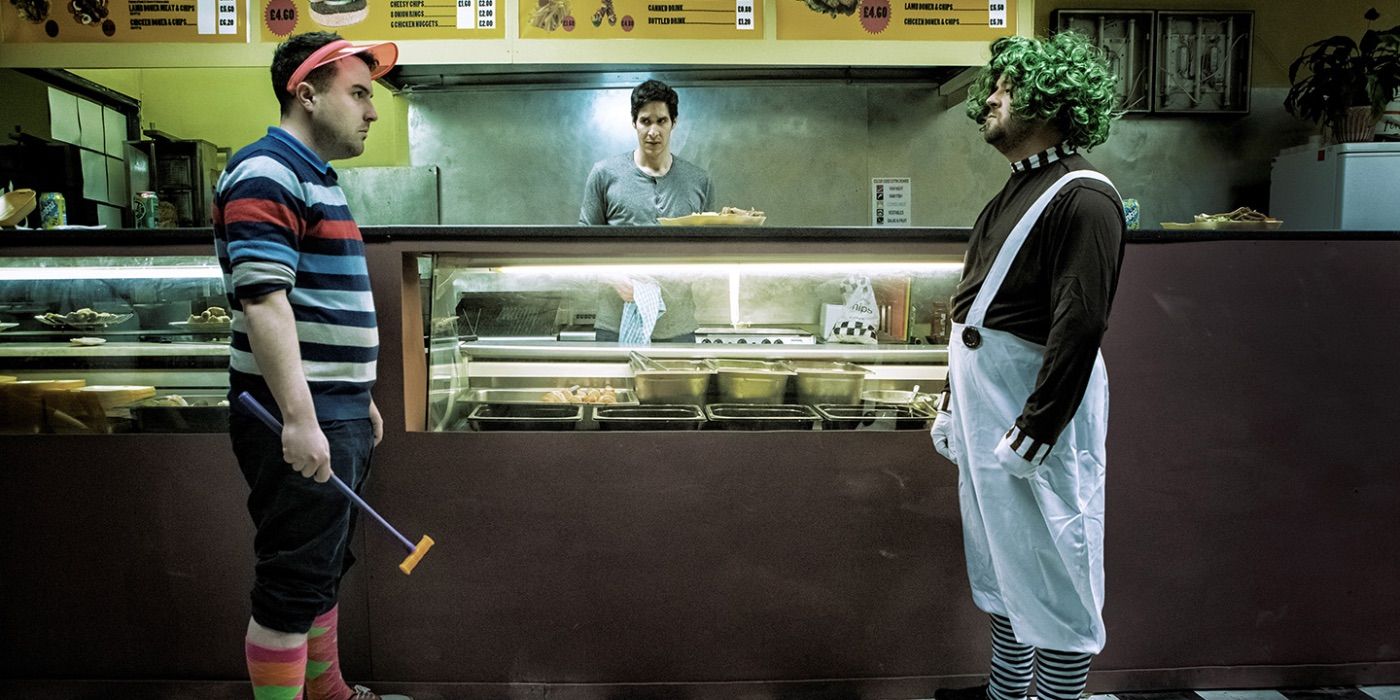 Two customers star at each other whilst Salah looks from behind the counter in K-Shop