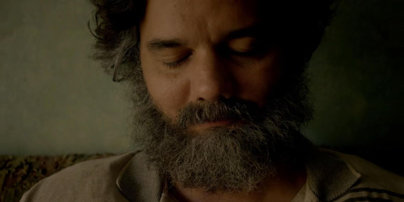 Wagner Moura in a closeup with long hair and beard looking down in Narcos, "Al Fin Cayo!"