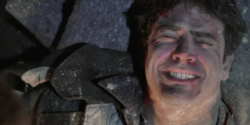 Lorcan (Jeffrey Dean Morgan) grimacing in pain as he lays on a pile of debris. 