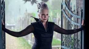 Joanna Lumley standing between open iron gates in Wednesday Season 2.