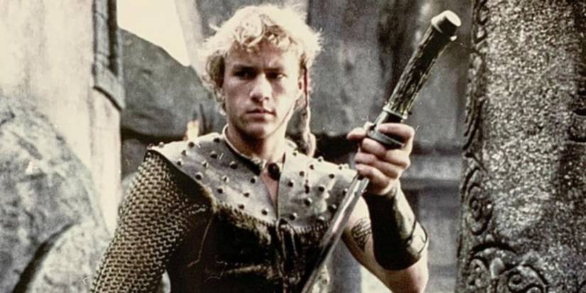 Connor (Heath Ledger) stands in the battlement of a castle sheathing his sword in Roar (1997).