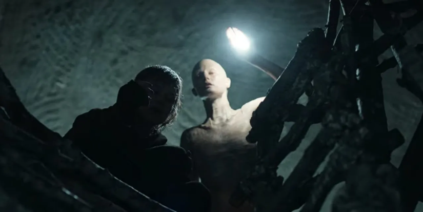 Alex looks down a hole with a pale creature behind her in 'Cracow Monsters.'