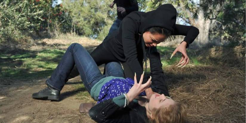 Alyssa Diaz and Skyler Samuels as Jasmine and Chloe fighting on the dirt with their claws out in 'The Nine Lives of Chloe King.'