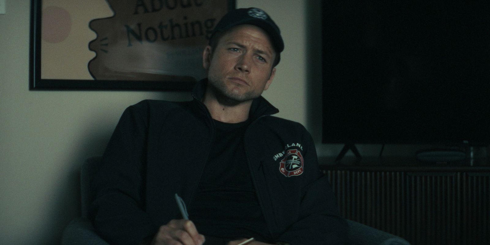 Taron Egerton taking notes and looking intetly at something off camera in Smoke