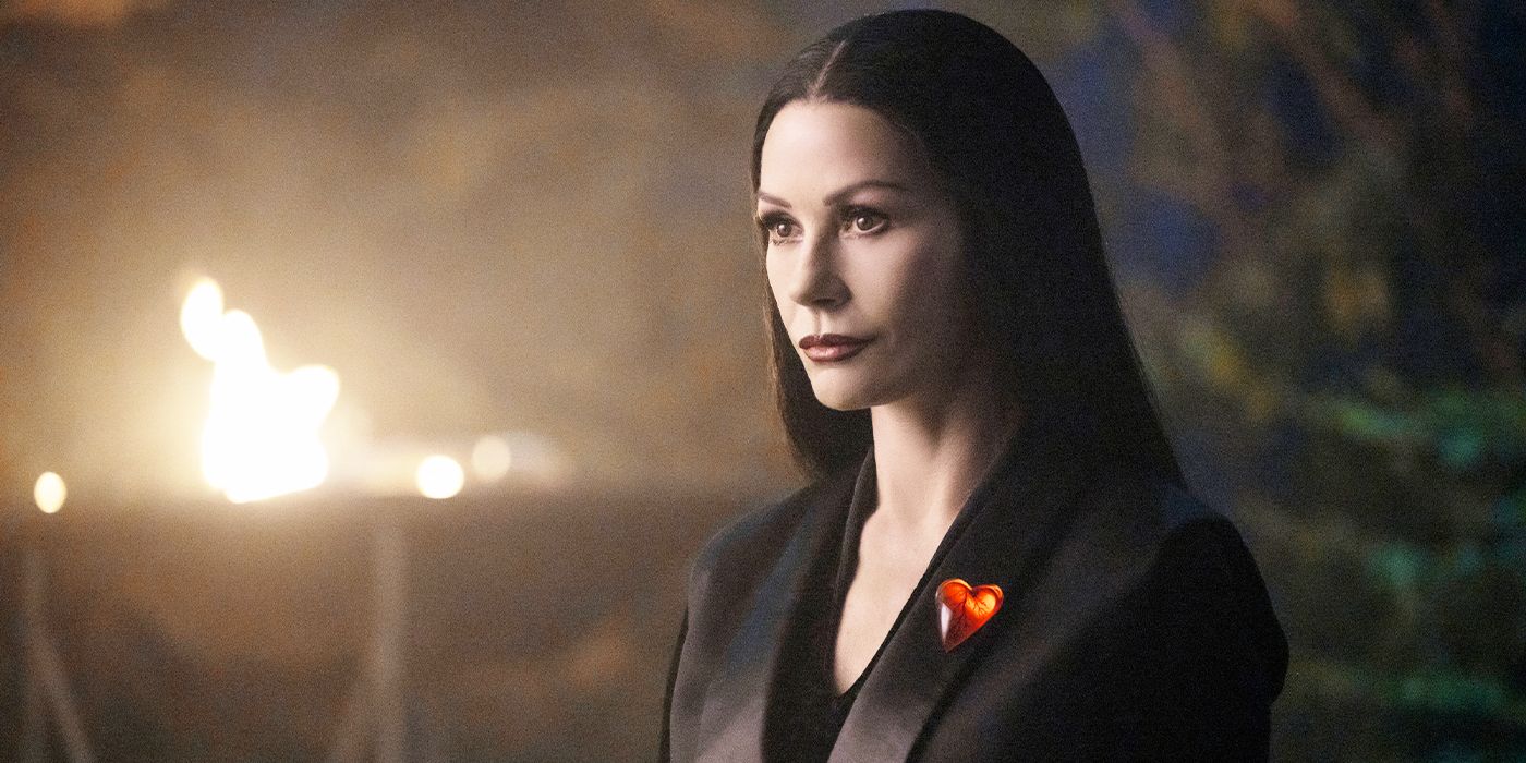 Catherine Zeta-Jones looking ahead, wearing a heart on her lapel in Wednesday Season 2.