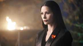 Catherine Zeta-Jones looking ahead, wearing a heart on her lapel in Wednesday Season 2.