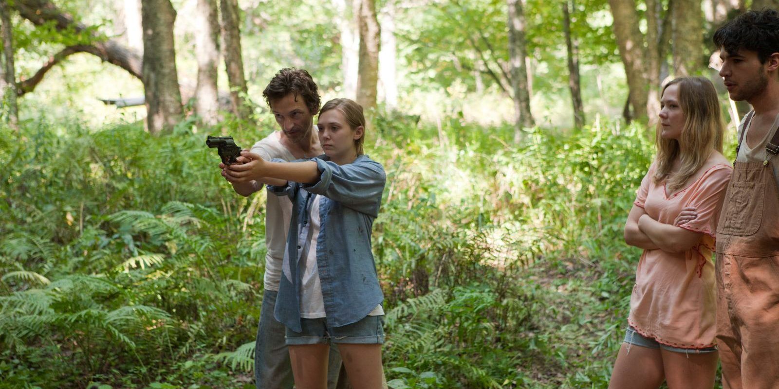Patrick (John Hawkes) teaching Martha (Elizabeth Olsen) to fire a handgun in the woods in Martha Marcy May Marlene